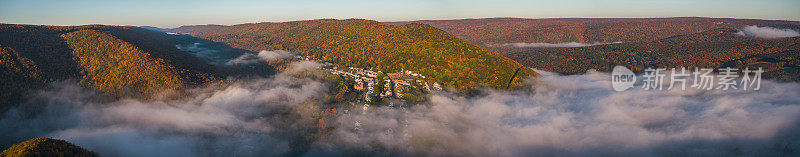 五彩缤纷的秋日里，阳光明媚的清晨，历史小镇吉姆·索普(Jim Thorpe)上空的山谷里，低云密布。美国宾夕法尼亚州卡本县波科诺地区。超大分辨率航拍全景图。